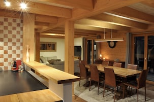 Una cocina moderna con encimera de madera y zona de comedor con una gran mesa y sillas de madera.