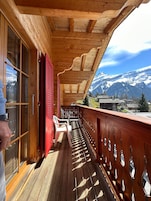 A wooden balcony with a view of snow-capped mountains.
