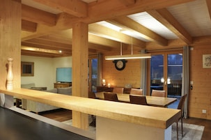 Un interior de madera con una mesa de comedor, sillas, un reloj y un televisor.
