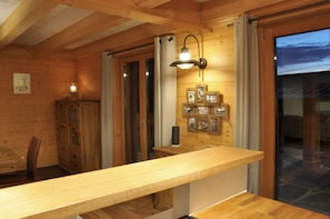 A wooden interior with a long counter, wooden cabinets, and framed pictures on the wall. - Chalet Edelweiss Stunning Glacier View (Ormont-Dessus)