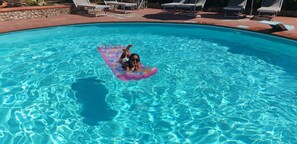 A swimming pool with clear blue water, lounge chairs, and a person floating on a floatation device. - Tuscan Villa, Private Pool and Tennis Court Garden,wi-fi, Ac, Pet Friendly (Rosignano Marittimo)