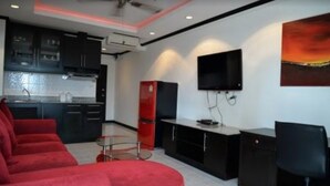 Una cocina moderna con armarios oscuros, un refrigerador rojo y un televisor de pantalla plana montado en la pared.