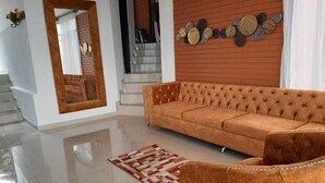 Uma sala de estar espaçosa com um sofá grande, um espelho e um objeto decorativo na parede.