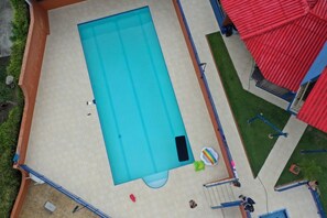 An aerial view of a swimming pool with a tiled deck, surrounded by a red-roofed structure and some greenery. - Country House in Cerritos, Pereira (Pereira)