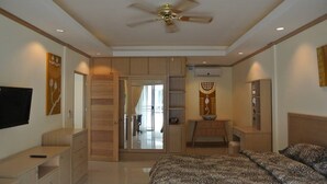 A bedroom with a bed, a ceiling fan, a TV, and a wardrobe. - Baan Suan Lalana Tc Floor 5 Room (Pattaya)