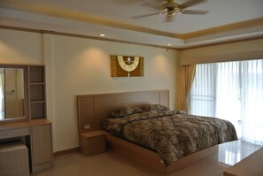 A bedroom with a large bed, a ceiling fan, a wall-mounted artwork, and a window with curtains. - Baan Suan Lalana Tc Floor 5 Room (Pattaya)