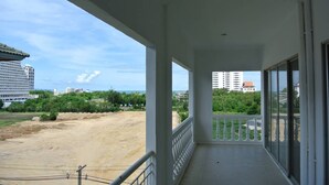 A balcony with a view of a sandy area and buildings in the distance. - Baan Suan Lalana Tc Floor 5 Room (Pattaya)
