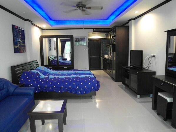 A modern bedroom with a bed, a desk, and a ceiling fan.