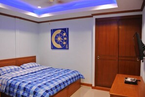 A bedroom with a bed, a wooden wardrobe, and a wall-mounted TV. - Baan Suan Lalana Te Floor 5 Room (Pattaya)