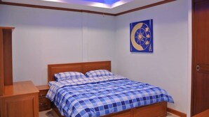A bedroom with a bed, wooden nightstands, a ceiling fan, and a wall-mounted artwork. - Baan Suan Lalana Te Floor 5 Room (Pattaya)