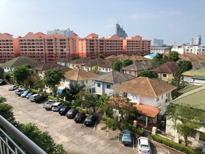 A residential area with multiple-story apartment buildings, a parking lot with several cars, and a construction crane in the background. - Baan Suan Lalana Sa Floor 4 Room 415 (Pattaya)