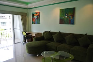 A modern living room with a sectional sofa, a glass coffee table, and two abstract paintings on the wall.