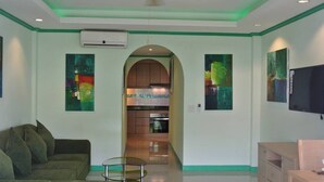 A living room with a sofa, a TV, and artwork on the walls. - Baan Suan Lalana Sa Floor 4 Room 415 (Pattaya)