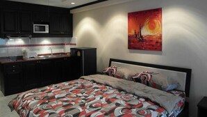 A modern bedroom with a large bed, a nightstand, and a painting of a sunset on the wall. - Jomtien Beach Condomium jbc A2 Floor 12 Room 7 (Pattaya)