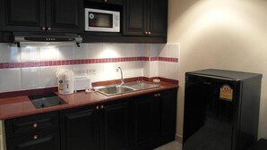 A compact kitchen with dark cabinets, a microwave, a sink, and a black refrigerator. - Jomtien Beach Condomium jbc A2 Floor 12 Room 7 (Pattaya)