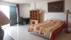 Une chambre d’hôtel avec un lit, un bureau, une chaise, une bibliothèque et une grande fenêtre.