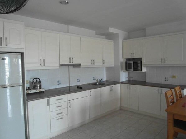 A modern kitchen with white cabinets, a stainless steel refrigerator, a microwave, and a kettle on the countertop. - View Talay Condo 2A Floor 16 Room (Pattaya)
