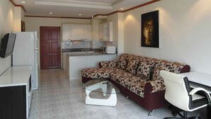 A modern living room with a sofa, a coffee table, a TV, and a kitchen in the background. - View Talay 1B Floor 6 Room (Pattaya)