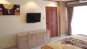 A bedroom with a TV mounted on the wall, a wooden cabinet, a door, and a window with curtains. - View Talay 1B Floor 6 Room (Pattaya)