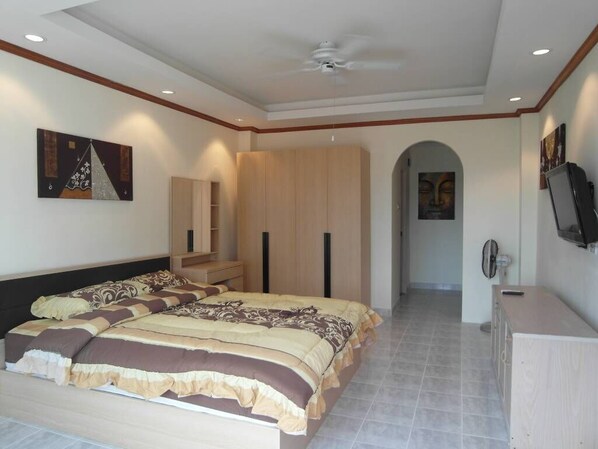 Un dormitorio con cama, armario, televisor y obras de arte en las paredes.