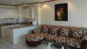 A modern living room with a sofa, a coffee table, and a kitchen area in the background. - View Talay 1B Floor 6 Room (Pattaya)