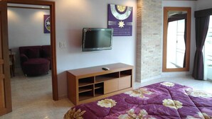 Una camera da letto con un letto, una televisione a muro, un armadio in legno e una finestra con tende.