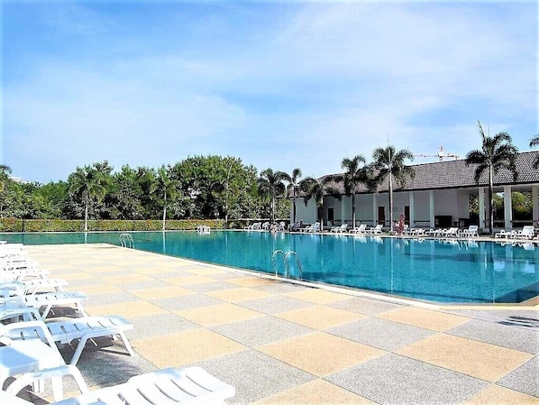 A swimming pool with lounge chairs and a building in the background.