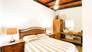 Un dormitorio con una cama, dos mesitas de noche, un aparador, un espejo y un ventilador de techo.