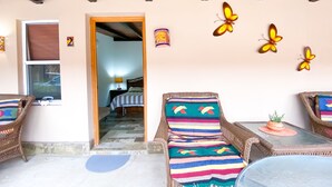 Una habitación acogedora con muebles de mimbre, una manta a rayas y decoración de mariposas en la pared.