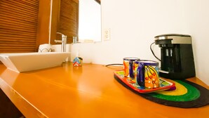 Un baño de hotel con lavamanos, espejo y cafetera en la encimera.