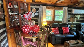 Interior acogedor de una cabaña con comedor, sofá de cuero y una pequeña mesa.