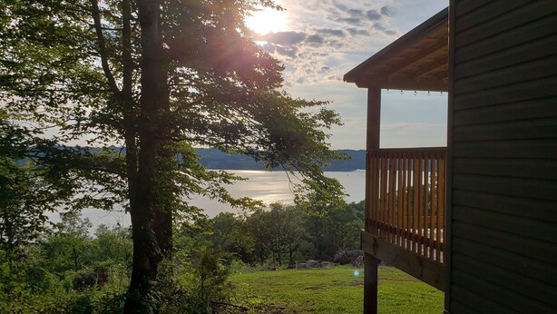 A wooden deck overlooking a lake with trees in the foreground.