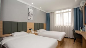 A hotel room with two beds, a desk, a chair, a window with curtains, and a framed picture on the wall. - Greentree Inn Shanghai Luojing Express Hotel (Shanghai)