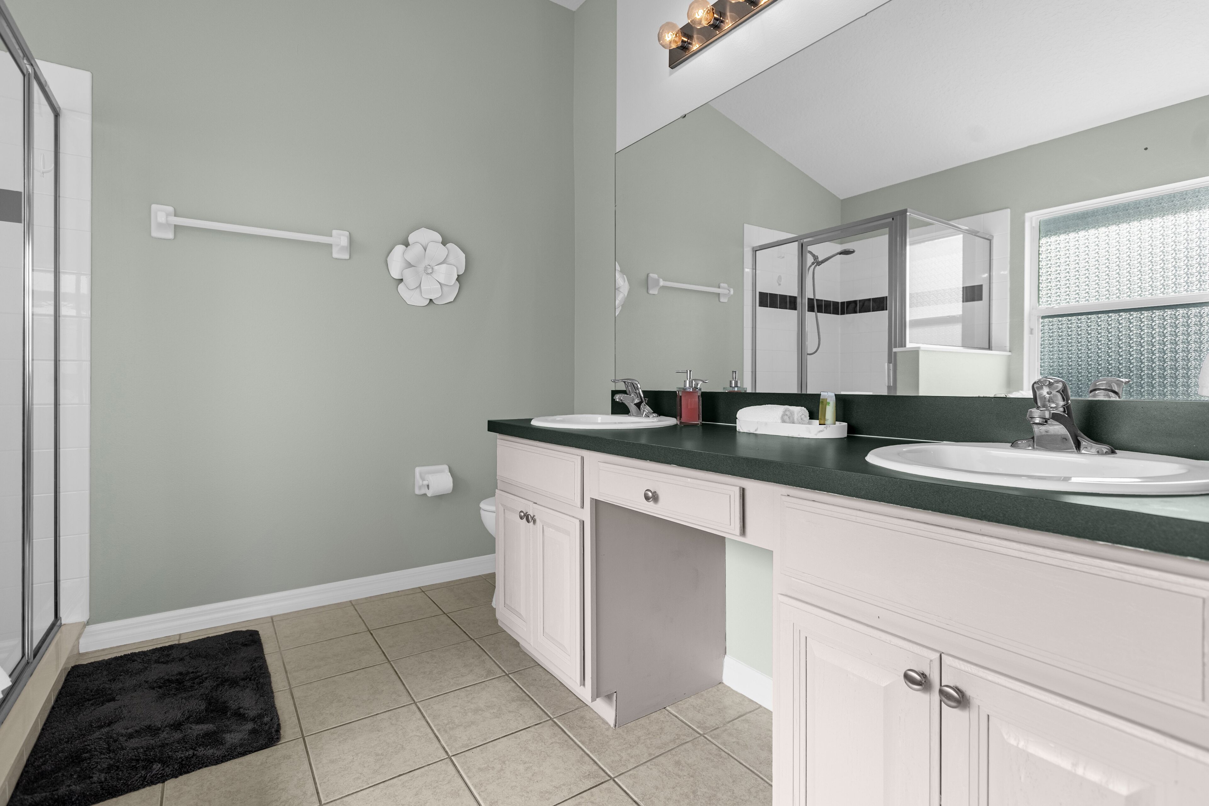 A modern bathroom with two sinks, a large mirror, and a shower area.