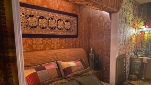 A cozy bedroom with a wooden headboard, a quilted bedspread, and a decorative tapestry on the wall. - An Indiana Jones Inspired Spectacular Adventure Movie Suite! (Chickamaga)