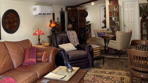 A cozy living room with a brown leather sofa, a wooden coffee table, and a patterned rug. - An Indiana Jones Inspired Spectacular Adventure Movie Suite! (Chickamaga)