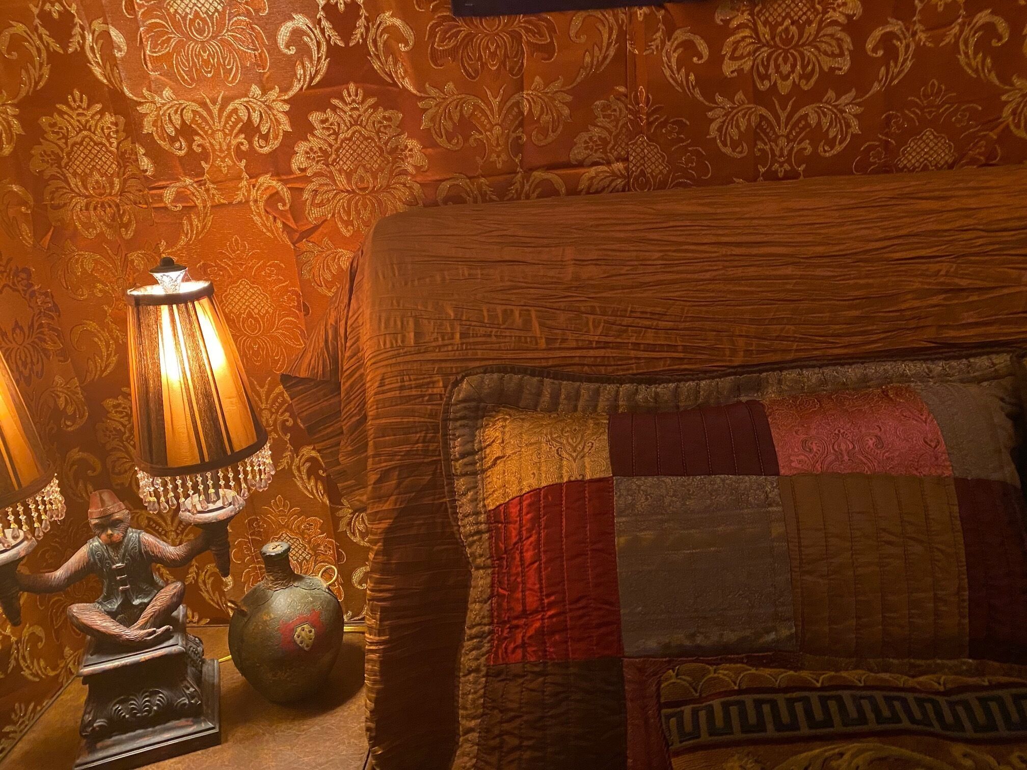 Een kamer met een bed, een lamp en een klein beeldje.