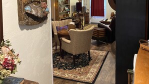 A cozy living room with a wooden floor, a bookshelf, a dining area with a table and chairs, and a large decorative piece on the wall. - An Indiana Jones Inspired Spectacular Adventure Movie Suite! (Chickamaga)