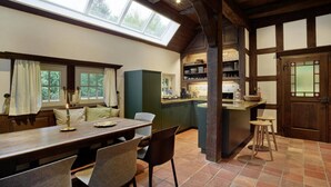 Una cocina acogedora con una mesa de madera, sillas y una isla integrada. Hay un ventanal que proporciona luz natural y vistas al exterior.