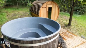 Un jacuzzi con revestimiento de madera y una terraza de madera con una mesa de picnic.