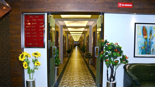 A hotel lobby with a reception desk, a 'No Smoking' sign, a 'Welcome' sign, and a hallway leading to rooms.