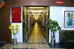 Un vestíbulo de hotel con una mesa de recepción, un cartel de 'No fumar' y un cartel de 'Bienvenido', además de un pasillo que conduce a las habitaciones.