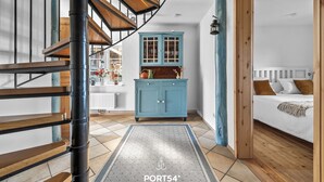 A staircase leading to a bedroom with a wooden headboard, a blue cabinet, and a white radiator.