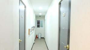 A narrow hallway with doors on both sides, a trash bin, and a fire extinguisher. - Oh My Inn (Seoul)