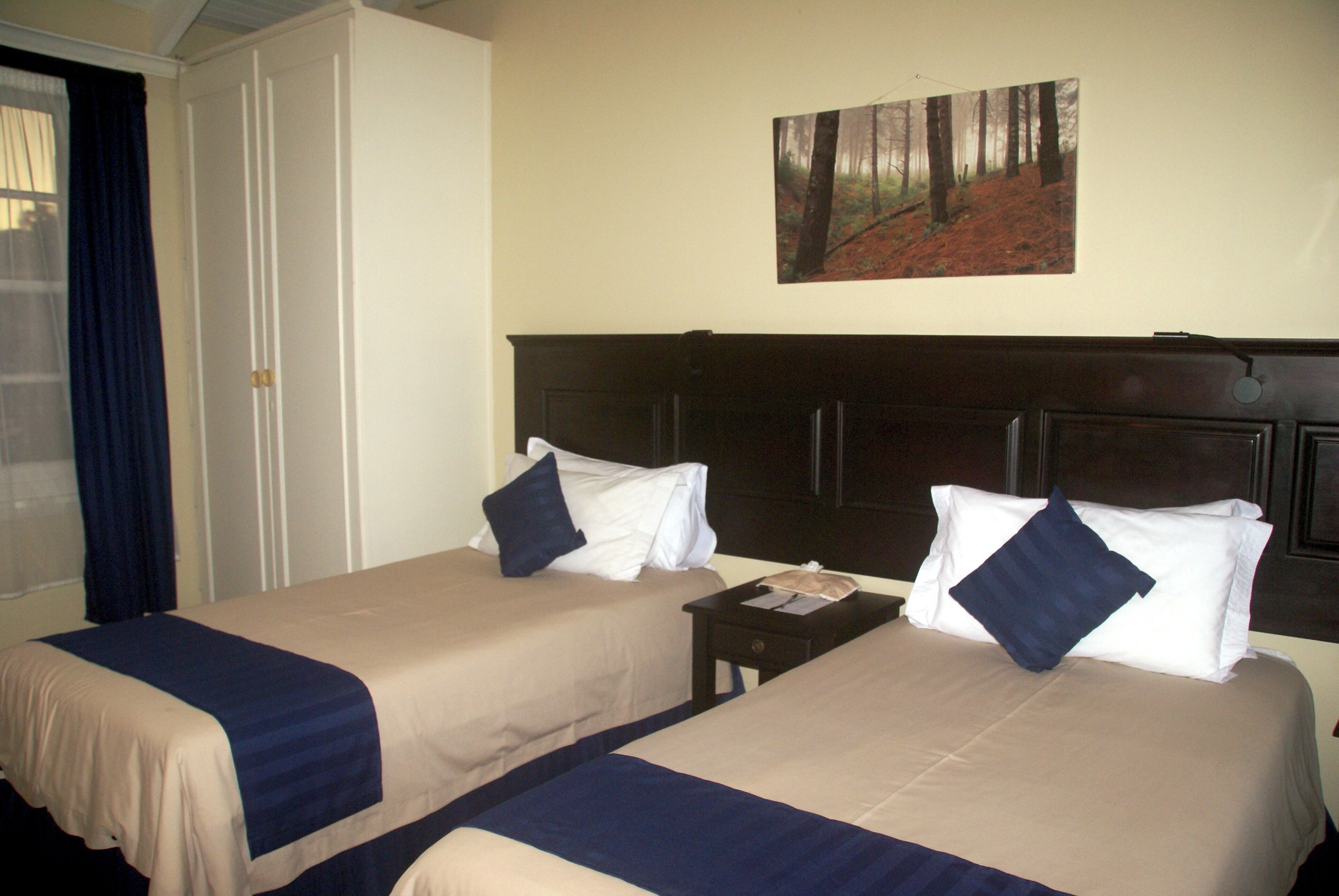 Two single beds with headboards, a nightstand, and a door with a curtain.