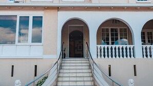 A two-story building with a central entrance, a staircase with metal railings, and a balcony with a balustrade. - Albion Manor (Durban)