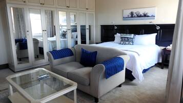 Habitación de hotel con cama, sofá, una mesita de centro de vidrio y un armario con espejos.