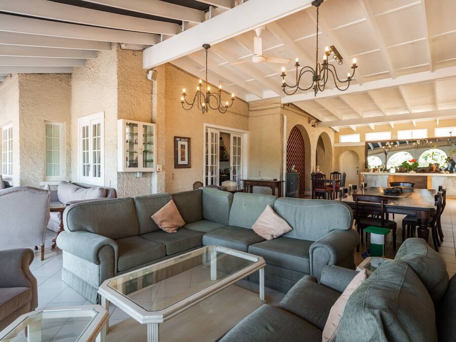 A spacious living area with a large sectional sofa, a glass coffee table, and a dining table with chairs.