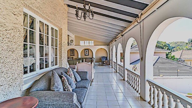 A covered outdoor area with a sofa and chairs, a chandelier, and a view of the surrounding neighborhood. - Albion Manor (Durban)