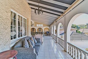 A covered outdoor area with a sofa and chairs, a chandelier, and a view of the surrounding neighborhood. - Albion Manor (Durban)